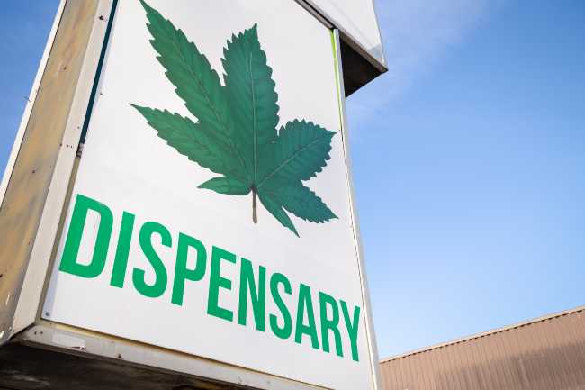Image of a white and green sign that says dispensary.