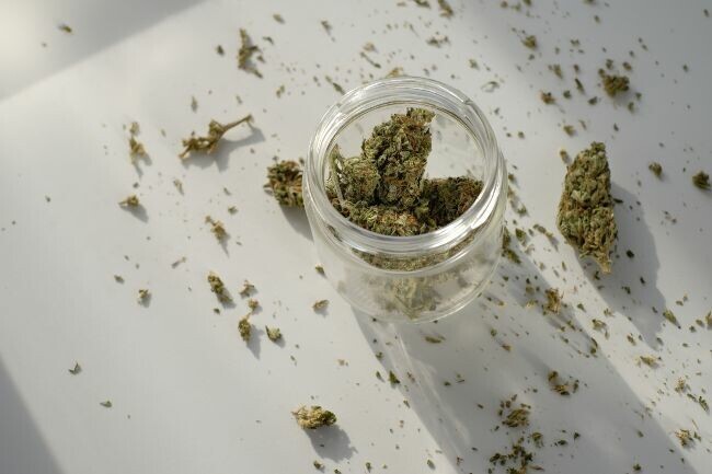 cannabis nugs in a glass jar on a white table