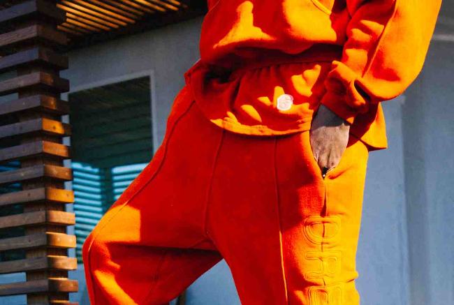 Image of a bright orange outfit, composed of sweatpants, t-shirt, and sweatshirt from the mid-torso to knee caps.