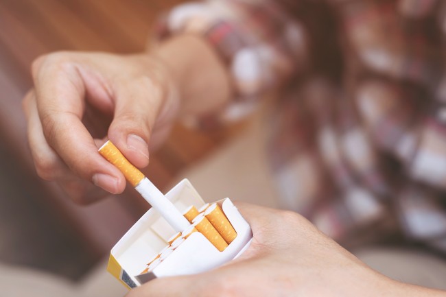 a man pulls out a cigarette from a pack of cigarettes