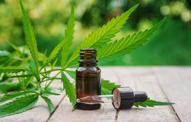 a bottle of cannabis tincture on a wooden table with the dropper laying next to it