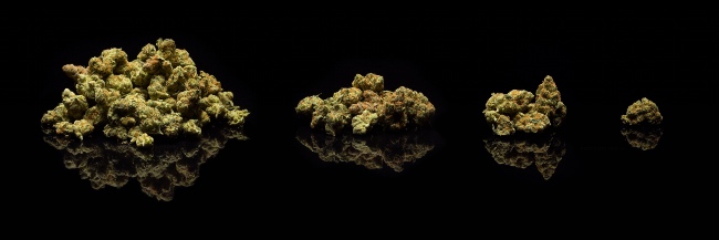 separate heaps of cannabis lie on a black background, lined up from largest to smallest