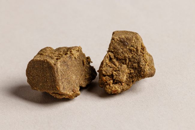 two small blocks of cannabis hash lay on a tan background