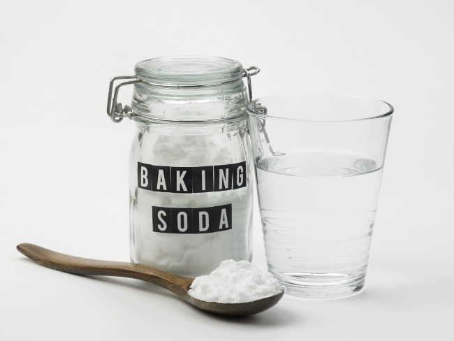 Glass jar with label reading “baking soda“ and filled with white powder.