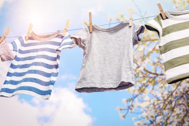 Clothes handing on a line outside with clouds above in the sky.