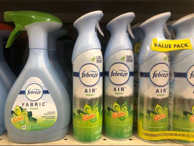 A row of Febreeze bottles on a tan grocery store shelf.