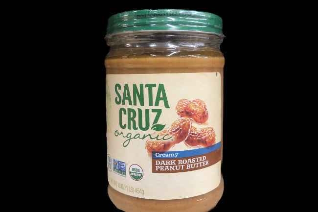 Santa Cruz peanut butter in a glass jar on a black background