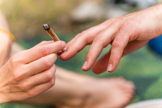 A hand passing a spliff to another hand.