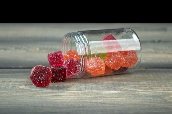 a clear bottle of multicolored sugar coated gummy edibles