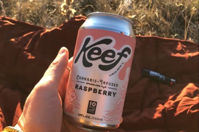 hand holding a soda can that has a pink label that says Keef on it