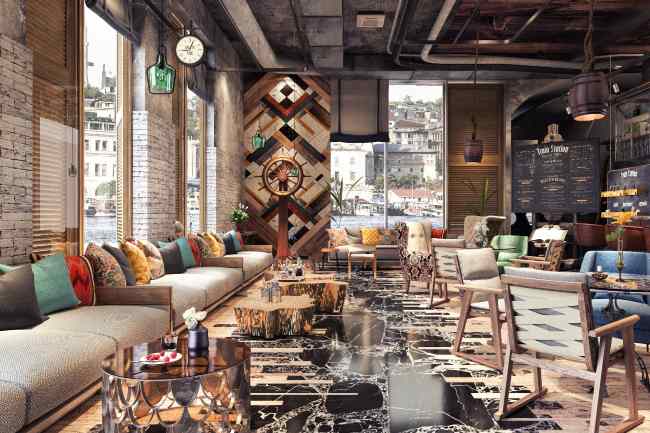 Inside of a cozy cafe with a menu board, couches with colorful pillows, and tables dispersed with chairs around.
