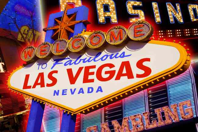black woman standing in front of a las vegas sign, smiling with her hands in her hand