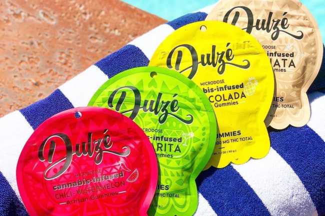 An array of different colored packaging for DULZE Edibles that are red, bright green, yellow, and tan