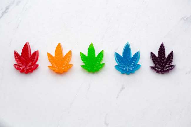 Four cannabis gummies in the shape of marijuana leaves.
