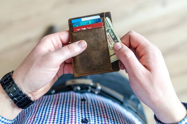 Someone getting out cash from their wallet to pay their weed delivery driver