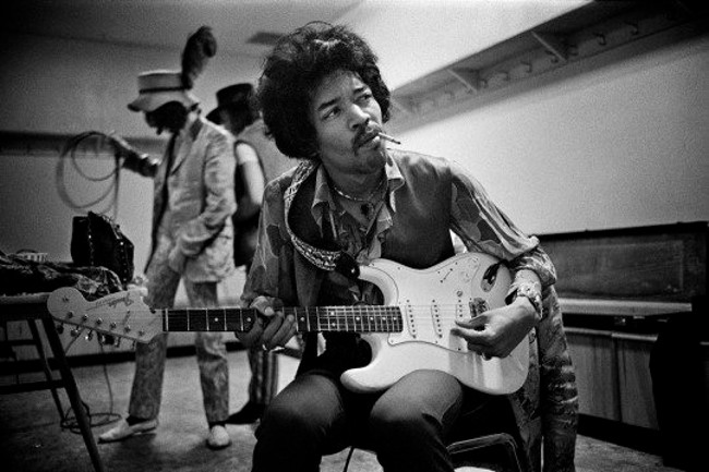 Jimmy Hendrix playing the guitar and smoking