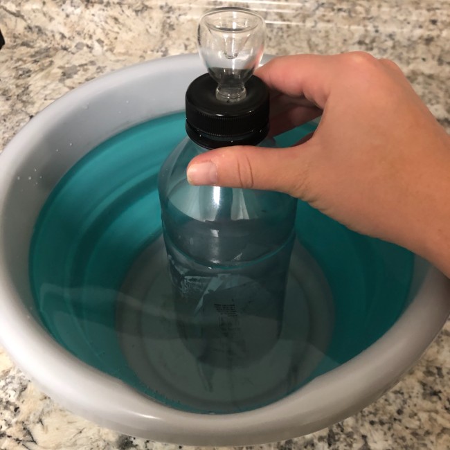 The grav bong waterbottle placed into a larger bucket filled with water