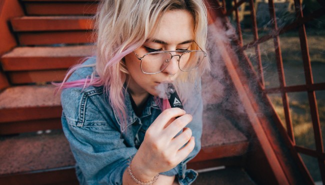 A woman smoking delta-8 out of a vape pen.