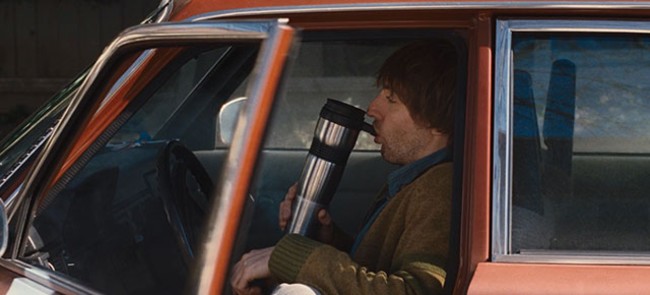 Guy from cabin in the woods smoking out of a coffee cup bong in his car